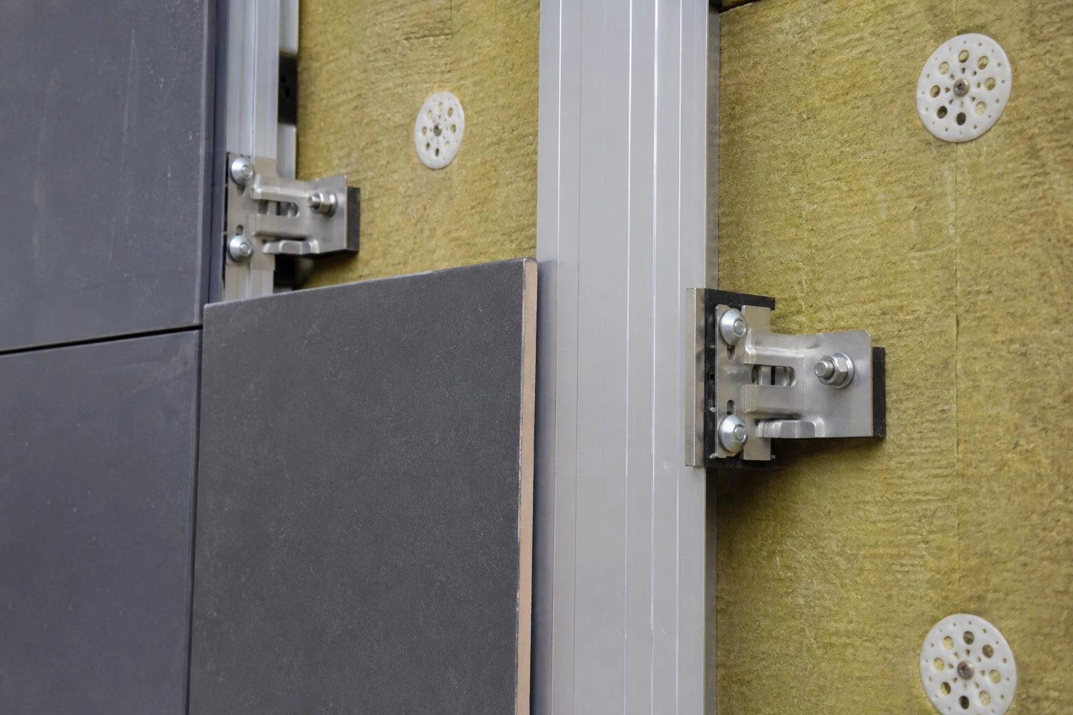 Adjustable clips and vertical rails supporting a ventilated cladding system over exterior insulation